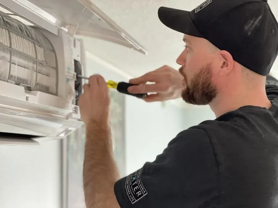 Technician uses screwdriver on open 12000 btu mini split best 2026 indoor unit