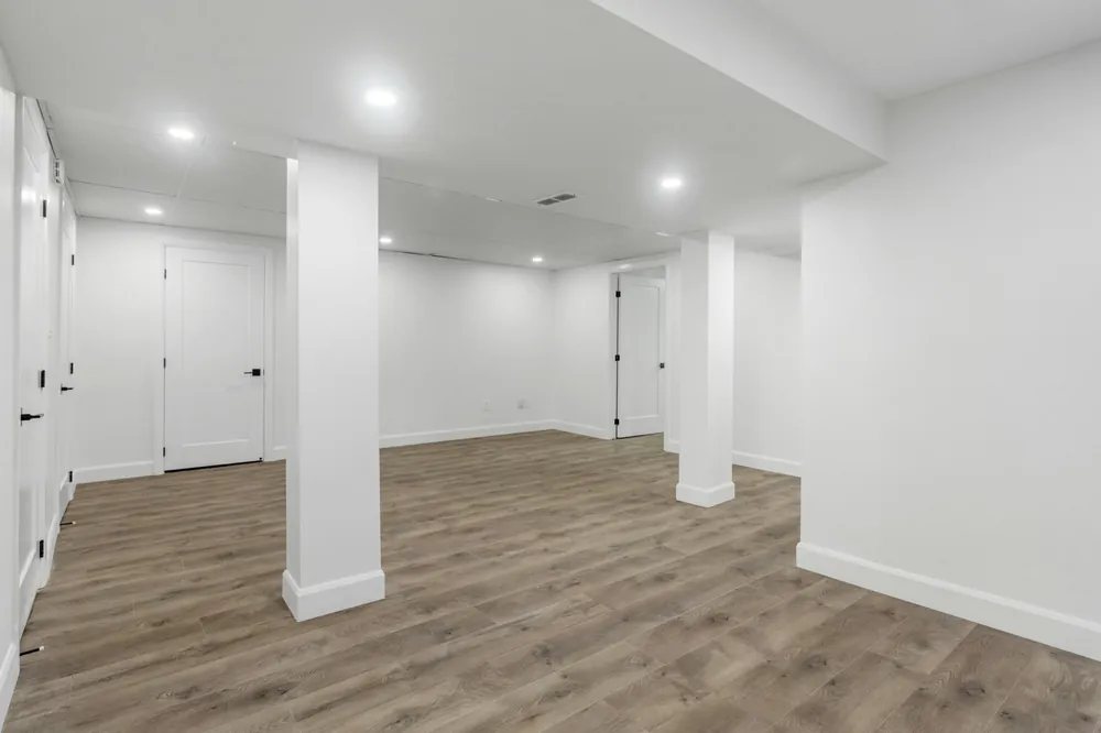 Finished basement with white walls, black hardware doors, and light flooring, ideal for the best basement mini split installation