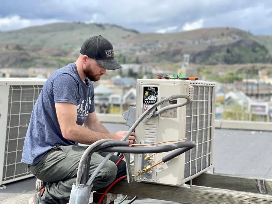 Installer connecting two insulated refrigerant line sets and the wiring to a mini split outdoor unit during a multi zone mini split DIY install