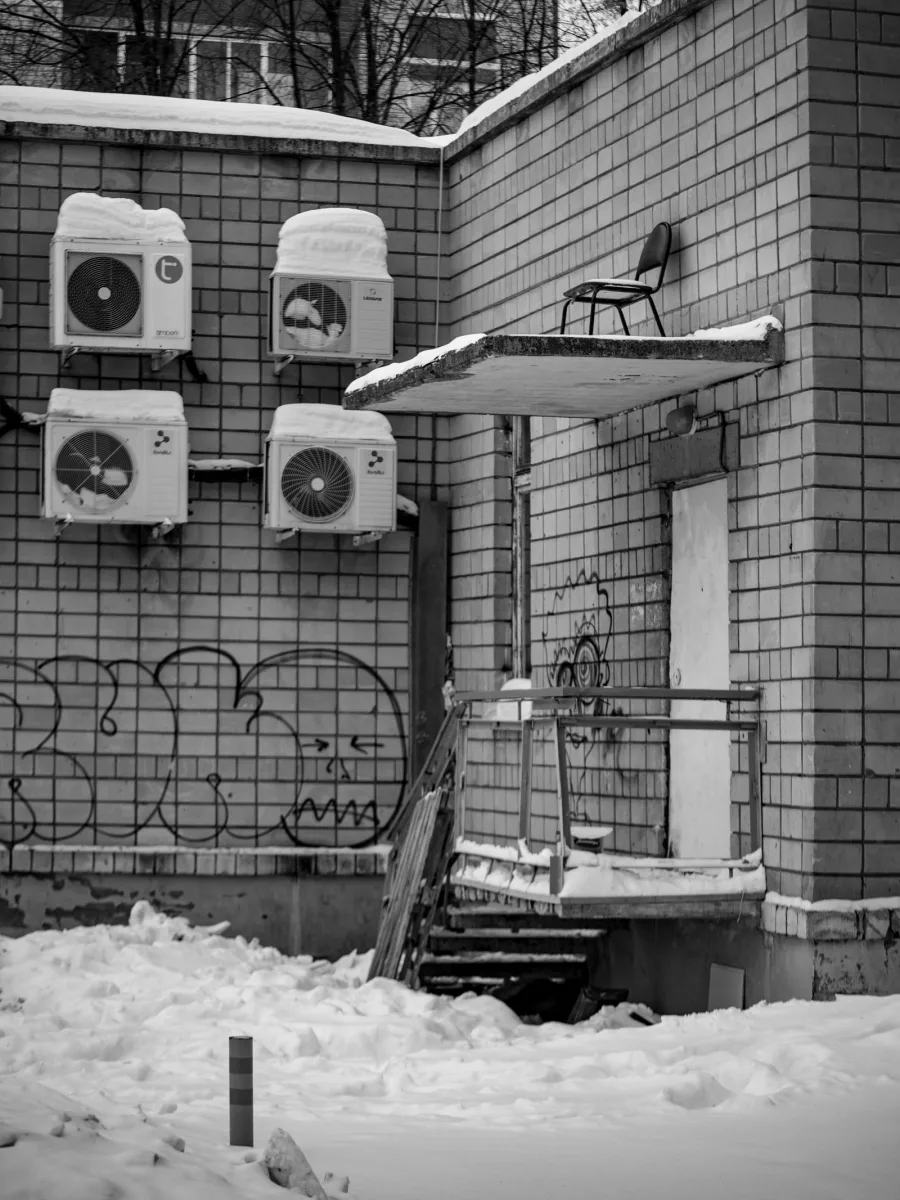 Four wall-mounted mini split outdoor units capped with snow on a brick building, the kind of cold weather a ductless heat pump temperature range has to cover